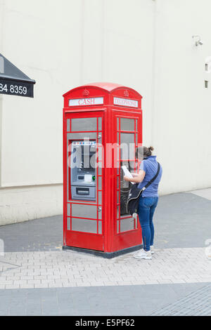 Telefonzelle umgewandelt in ein ATM Geldautomaten und ein öffentliches Telefon, London, UK Stockfoto