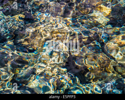 Abstrakte farbenfrohe Flachwasser Ripple Muster oben sonnenbeschienenen Kiesel im Bach Bett, Schottland, UK Stockfoto