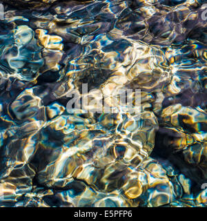Abstrakte farbenfrohe Flachwasser Ripple Muster oben sonnenbeschienenen Kiesel im Bach Bett, Schottland, UK Stockfoto