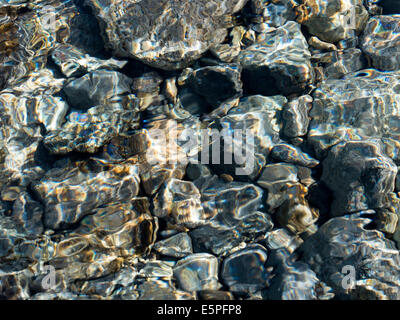 Abstrakte farbenfrohe Flachwasser Ripple Muster oben sonnenbeschienenen Kiesel im Bach Bett, Schottland, UK Stockfoto