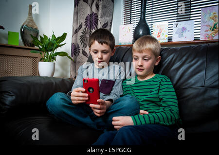 2 Jungs 8 9 10 11 Spielen eines Computerspiels auf Handy, auf sofa Stockfoto