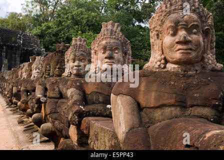 Geschnitzten Stein Krieger Götter entlang der Brücke über den Graben nahe dem südlichen Eingang zum Angkor Thom. Detail der Steinköpfe auf Brücke, die Eingabe von Angkor Thom, Kambodscha. Süd-Tor nach Angkor Thom in Kambodscha ist gesäumt von Kriegern und Dämonen. Stockfoto