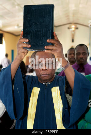 Römisch-katholischer Priester hält Bibel im sonntäglichen Gottesdienst in Maiduguri, Nigeria Stockfoto