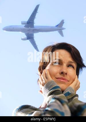 Frau leidet Lärm von niedrig fliegenden Flugzeug. Stockfoto