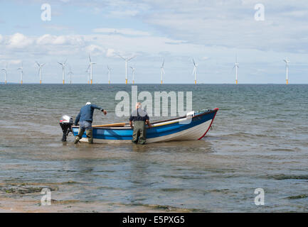 Zwei Fischer startet ein Boot mit Offshore-Windpark hinter Redcar, Redcar und Cleveland, England, UK Stockfoto