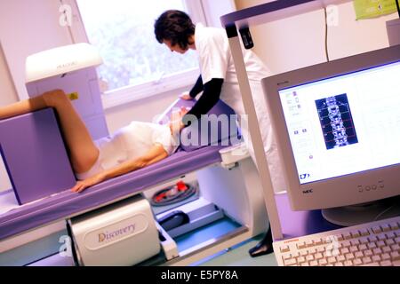 Ein Arzt benutzt ein Knochen Densitometer zur Messung der optischen Dichte der unteren Wirbelsäule der Patientin zu diagnostizieren Stockfoto