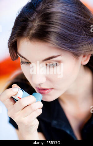 Frau mit einem Aerosol-Inhalator, der Erweiterung der Bronchien zur Behandlung von Asthma enthält. Der Inhalator weitet Lunge Atemwege Stockfoto