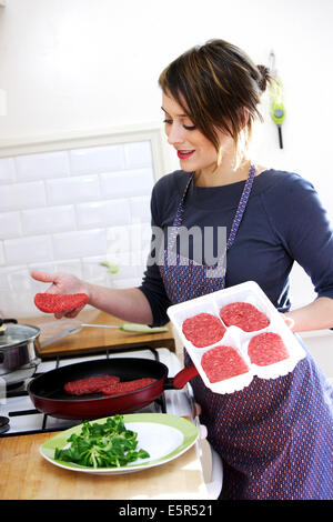 Frau Kochen Hackfleisch Burger. Stockfoto