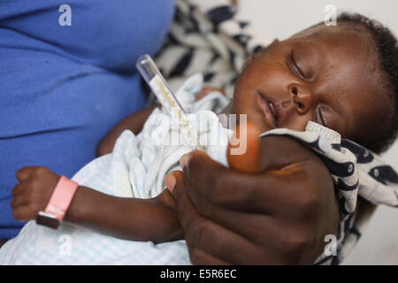 Überprüfen die Temperatur der Kinder leiden unter Mangelernährung in einem therapeutischen Feeding Center in Monrovia, Liberia, Stockfoto