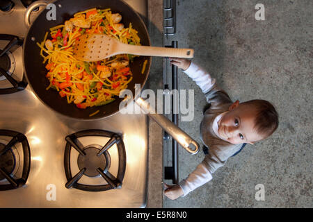 14 Monate altes Baby durch eine Küche Herd stehen. Stockfoto