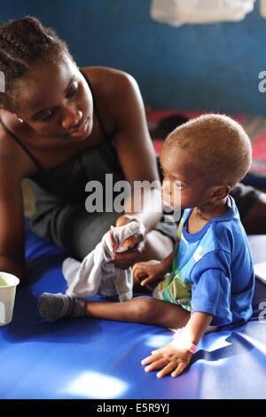 Mutter füttert ihr unterernährten Kind mit therapeutischer Milch in einer therapeutischen Ernährungszentrum in Monrovia, Liberia, Stockfoto