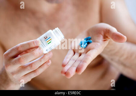 Mann, die Einnahme von Alli, Alli ist eine halbe Dosis Version des Diät Medikaments Xenical (Orlistat) hergestellt von GlaxoSmithKline (GSK). Stockfoto