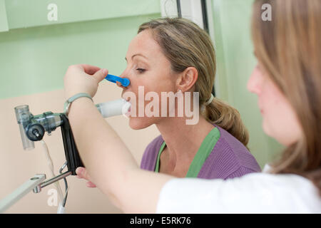 Frau durchläuft eine Lungenfunktion testen mit einem Spirometer, die den Höchstsatz misst an der Luft ausgeschlossen ist die Stockfoto