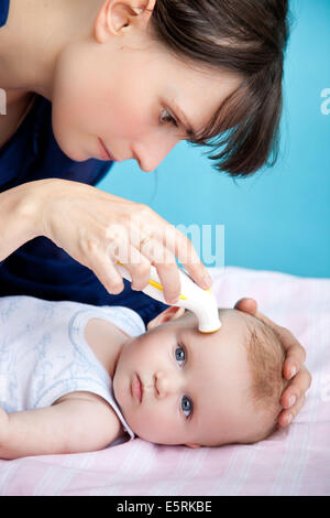 Überprüfen die Temperatur des 5 Monate altes Baby mit Stirn-Thermometer. Stockfoto