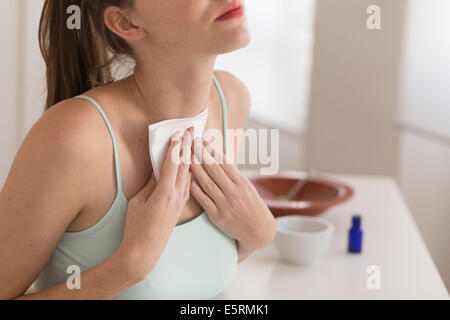 Frau Anwendung ein Pflaster auf die Schilddrüse. Stockfoto