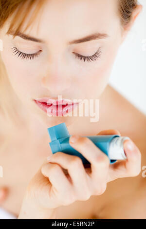 Frau mit einem Aerosol-Inhalator, der Bronchodilatator zur Behandlung von Asthma, den Inhalator enthält weitet Lunge Atemwege Stockfoto