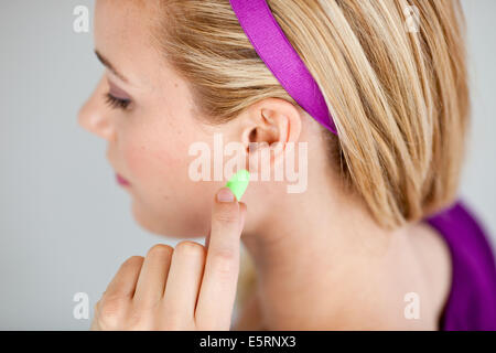 Frau trägt Ohrstöpsel. Stockfoto