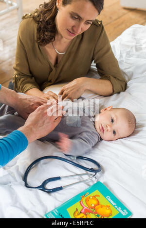 Arzt den Bauch ein 5 Monate altes Baby junge abtasten. Stockfoto