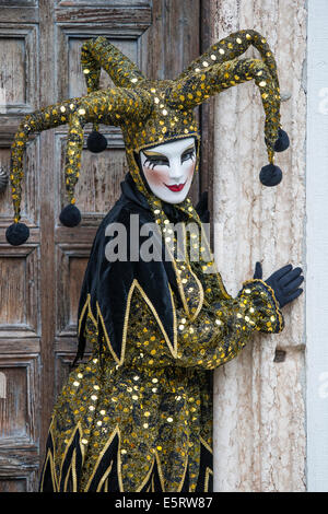 Jester oder Clown in Schwarz & gold Kostüm vor der Kirche San Zaccaria während des Karnevals in Venedig. Stockfoto