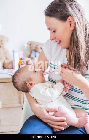 Mutter gibt ihr 3 Monate altes Baby junge Doliprane® mit einer Pipette. Stockfoto