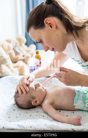 Mutter gibt ihr 3 Monate altes Baby junge Doliprane® mit einer Pipette. Stockfoto