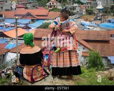 Zwei Frauen der Flower Hmong und Baby mit Blick auf den Markt von Bac Ha, Vietnam Stockfoto