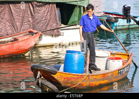 Chinesischer Mann Zeilen Boot durch den Causeway Bay Typhoon Shelter, Hong Kong. Stockfoto