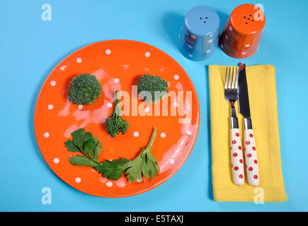 Gesunde Ernährung gesunde Ernährung Konzept mit glücklichen Smiley Gesicht hergestellt aus Brokkoli und Sellerie auf einem Spaß orange Tupfen Teller Stockfoto