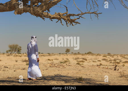 Arabische Mann in Tracht steht in der Wüste Stockfoto