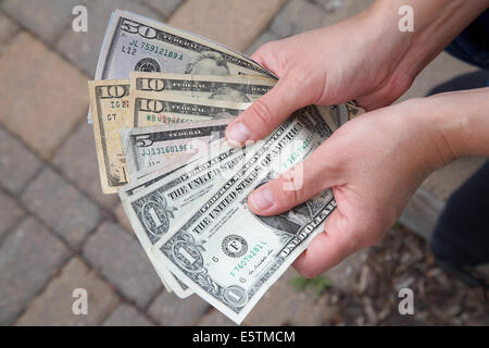 Eine Person hält und amerikanische Dollarnoten zu zählen. Stockfoto