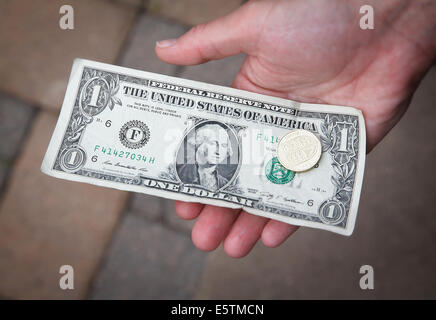 Person, die einen 1-Dollar-Schein und eine britische Pfund-Münze. Stockfoto