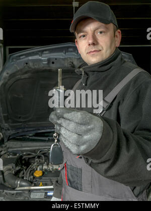 Kfz-Mechaniker hält einen Autoschlüssel des reparierten Autos warten an den Kunden übergeben werden Stockfoto