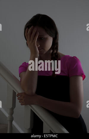 Junge Frau hand trägt ein pinkes Top und Haar in Plats stehend auf der Treppe im Innenbereich, aufs Gesicht. Stockfoto