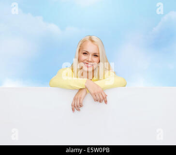 lächelnde Frau in Pullover mit leeren weißen Tafel Stockfoto