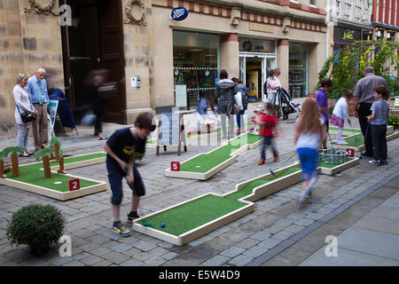 Kinder spielen im Freien Mini-9-Loch-Crazy-Golfplätze, Minigolf, Mini-Putt, Abenteuer-Minigolf oder Putt-Putt im Stadtzentrum von Manchester. Großbritannien, 6. August 2014. Children's Crazy Golf im Dig the City Deansgate, einem jährlichen Urban Gardening Festival, das vom Business Improvement District in Manchester veranstaltet wird – BID. Blumenschmuck, der das Stadtzentrum von Manchester umwandelte, als Dig the City zurückkehrte. Sechzehn Schauveranstaltungen, die während des Urban Gardening Festivals vom 2. Bis 10. August zu sehen waren. Stockfoto