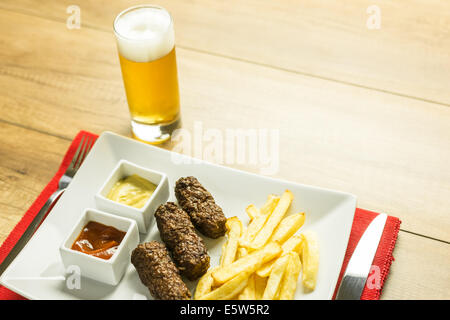 Traditionellen rumänischen Mici und Pommes Frites mit Ketchup, Senf und Bierglas Stockfoto