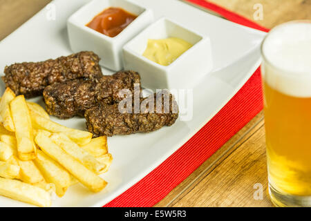 Traditionellen rumänischen Mici und Pommes Frites mit Ketchup, Senf und Bierglas Stockfoto