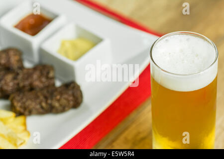 Traditionellen rumänischen Mici und Pommes Frites mit Ketchup, Senf und Bierglas Stockfoto