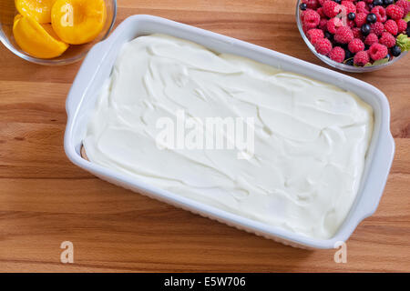 Ein Schuss von den Prozess der Vorbereitung hausgemachten Biskuit mit Dosenpfirsiche, Mascarpone und frischen Himbeeren. Stockfoto