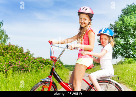 Zwei kleine Mädchen sitzen auf einem Fahrrad im freien Stockfoto