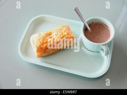 Patty und heißem Kakao in einem blauen Teller am Esstisch. Stockfoto