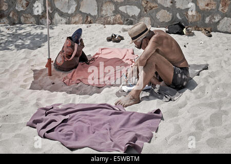 Mann besetzen seine Zeit am Strand durch ein Wort Puzzle Quiz ausfüllen. Stockfoto