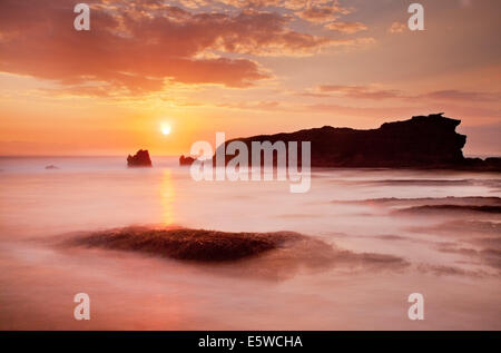 Sonnenuntergang über dem Meer Stacks. Schöne orange sky mit Golden Sun kurz vor dem Horizont über misty Meer mit Silhouettiert rock Stack. lange Belichtung foto Technik Stockfoto