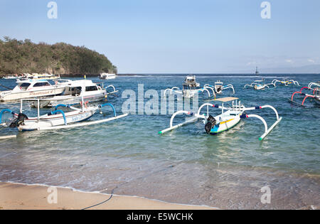 Flotte der traditionellen indonesischen jukung Fischerboote in padangbai Bay Harbour, Bali. Schöne, klare blaue Meer mit Sammlung von Boote schwimmend Stockfoto