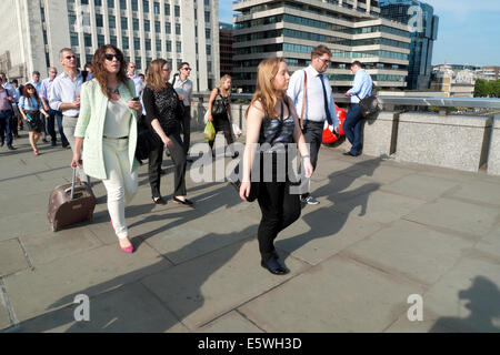 Frau mit Rädern Gepäck und Personen, die zu Fuß über London Bridge über die Themse während der Rush Hour nach der Arbeit im Sommer London UK KATHY DEWITT Stockfoto