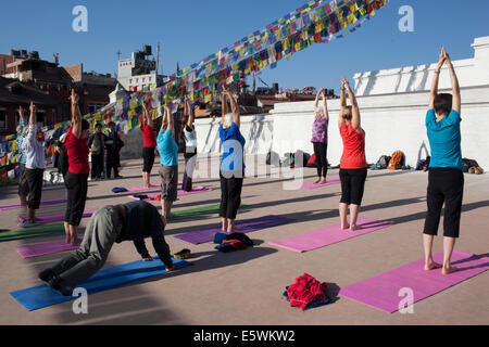 Die tibetischen buddhistischen Stupa von Boudhanath dominiert die Skyline von Kathmandu. Menschen, die Yoga in der Monring zu praktizieren. Stockfoto