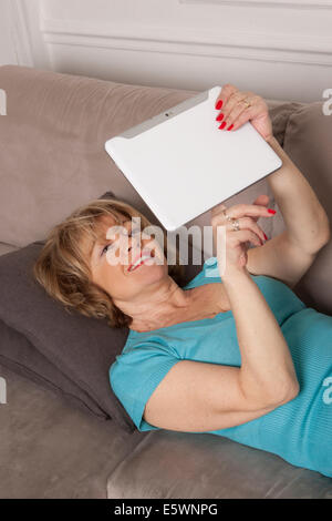 Frau mit digital-Tablette auf sofa Stockfoto