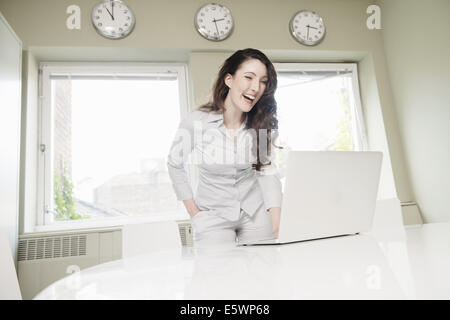 Junge Geschäftsfrau lachen über laptop Stockfoto