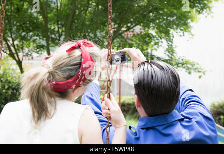 Rückansicht des jungen Vintage paar nehmen Selfie mit Kamera im Garten Stockfoto