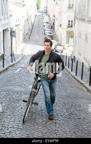Mitte erwachsenen Mannes hochschieben Fahrrad gepflasterten Stadt Straße